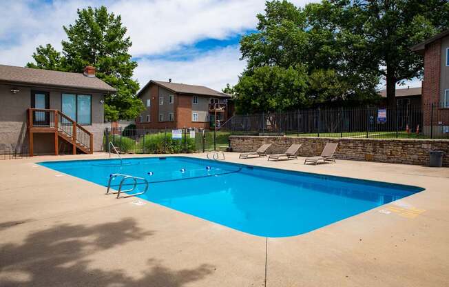 A blue swimming pool surrounded by a fence and trees.