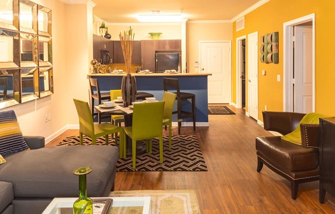 a living room and dining room with a kitchen in the background