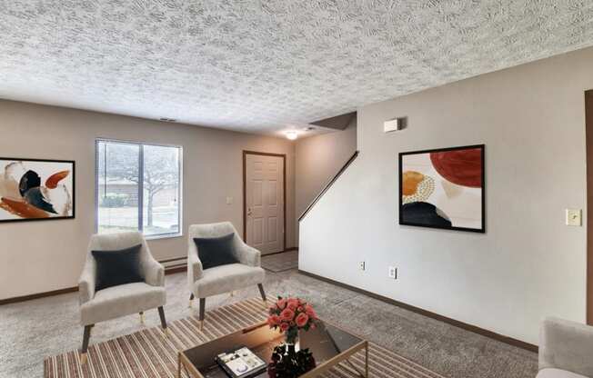 a living room with two chairs and a coffee table    and a staircase