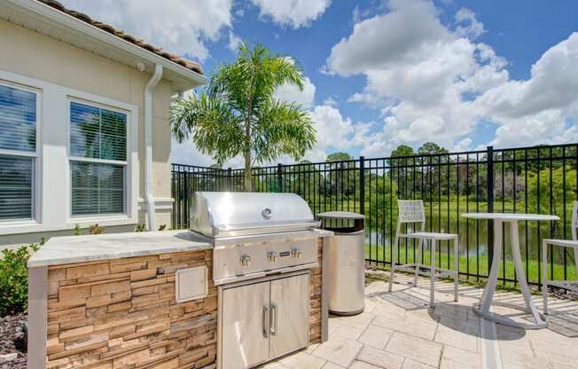 Grill and table with chairs and a pond in the background at flats at sundown luxury apartments in north port florida