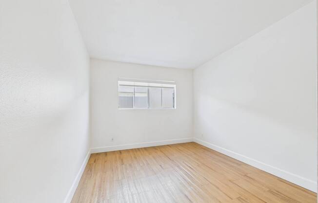 Empty room with wooden floor and a window.