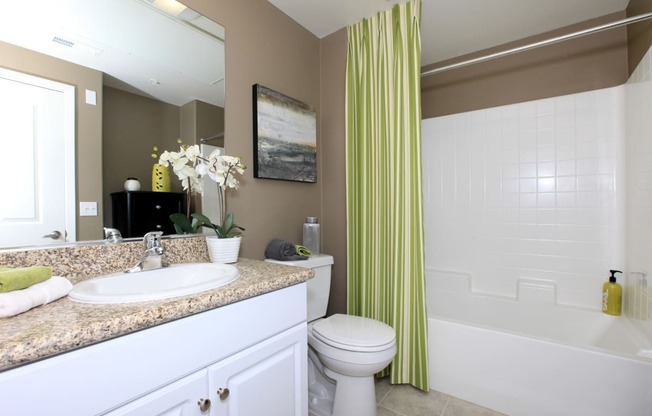 a bathroom with a green shower curtain and a sink and a toilet