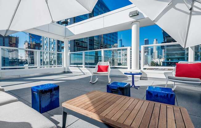 A wooden table is in the middle of a patio with white chairs and umbrellas.