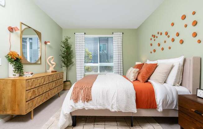 A bedroom with a bed, dresser, and mirror.