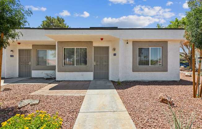 a white house with two doors and a gravel driveway