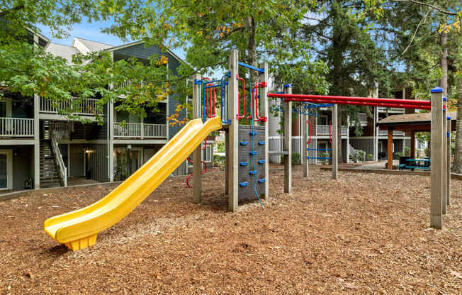 a playground with a yellow slide and red and blue slides