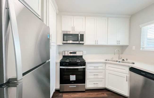 a small kitchen with white cabinets and stainless steel appliances