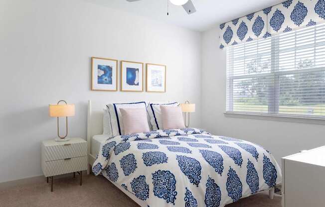 A bedroom with a bed, nightstands, and pictures on the wall.