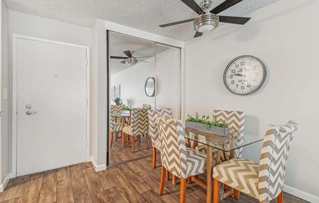A dining room with a glass table and chairs with a mirror above it.