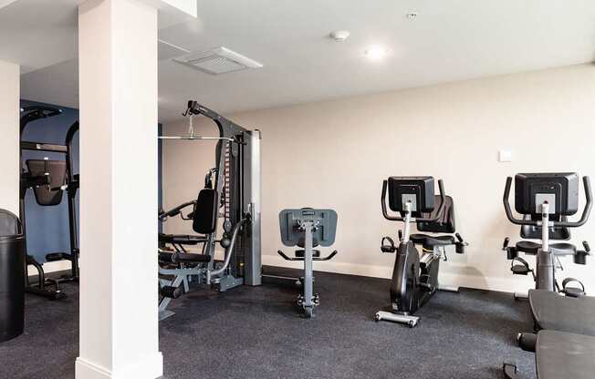 A gym with a row of exercise bikes and a weight machine.