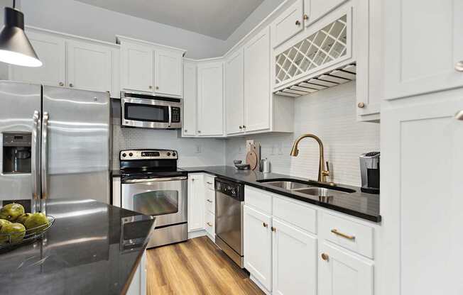 A modern kitchen with white cabinets and stainless steel appliances.
