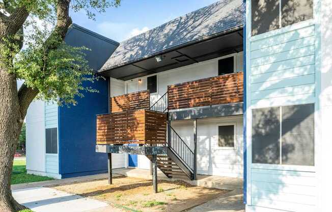 a building with a balcony and a tree in front of it