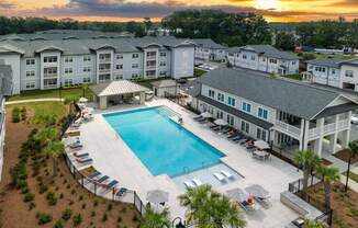 an aerial view of an apartment complex with a swimming pool at sunset