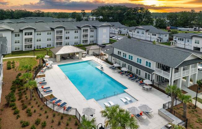 an aerial view of an apartment complex with a swimming pool at sunset