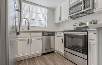 a kitchen with white cabinets and stainless steel appliances  at The Resort at Encinitas Luxury Apartment Homes, Encinitas, California