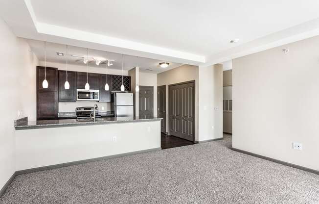 an empty living room and kitchen with a counter top and a door
