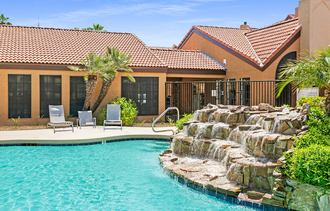 a swimming pool with a waterfall in front of a house