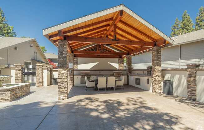 a large outdoor kitchen with stone pillars and a wooden roof