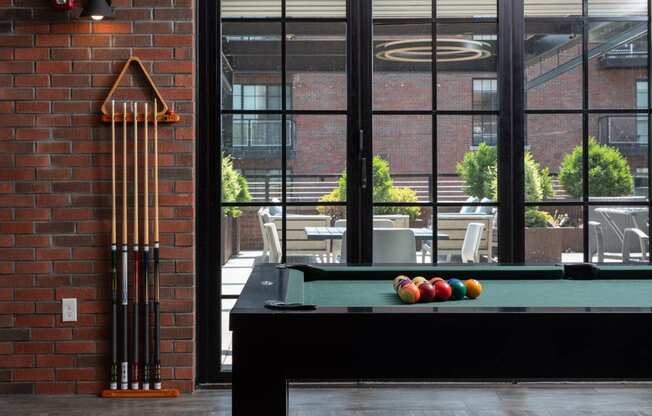 a pool table in a living room with a brick wall