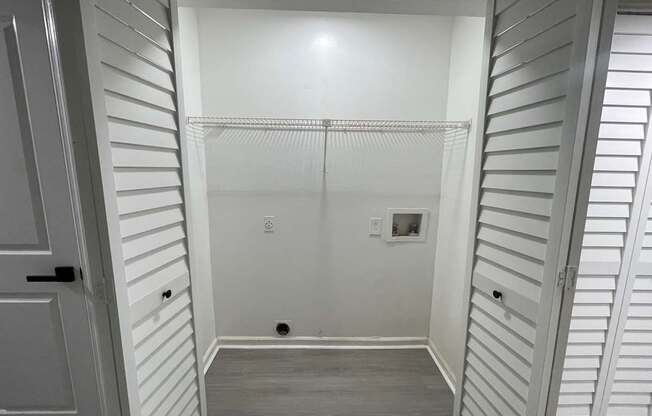 A white closet with a door and a shelf.