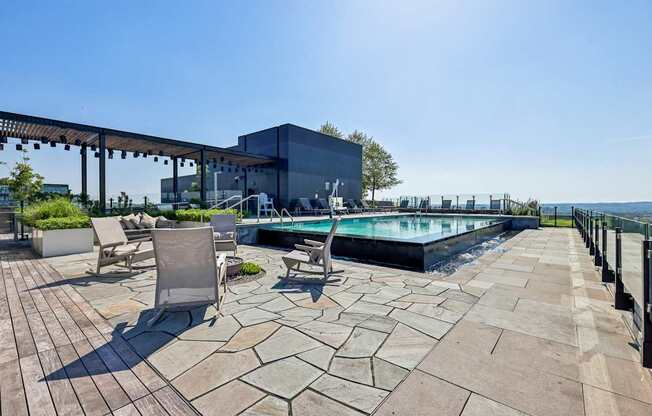 A pool area with a patio and chairs.