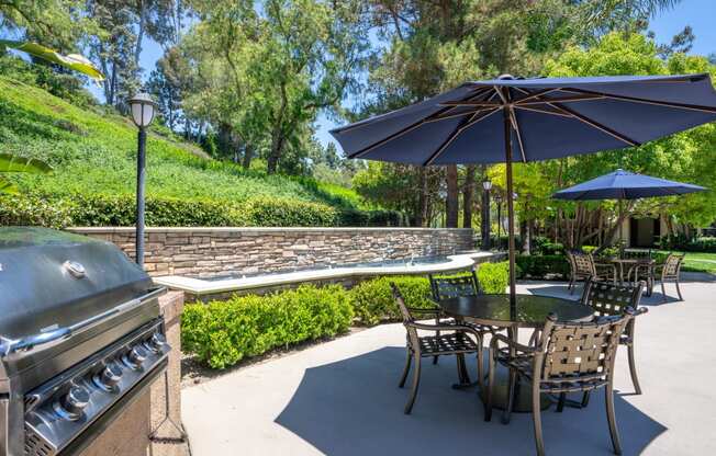 a patio with a grill and tables with umbrellas