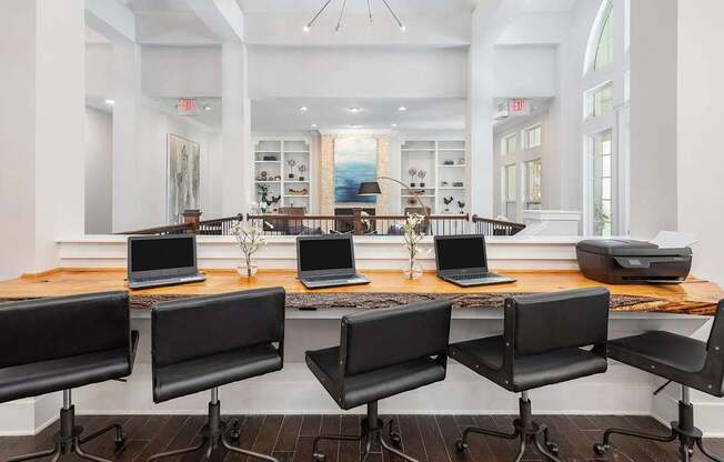 A room with a long table and chairs with laptops on it.