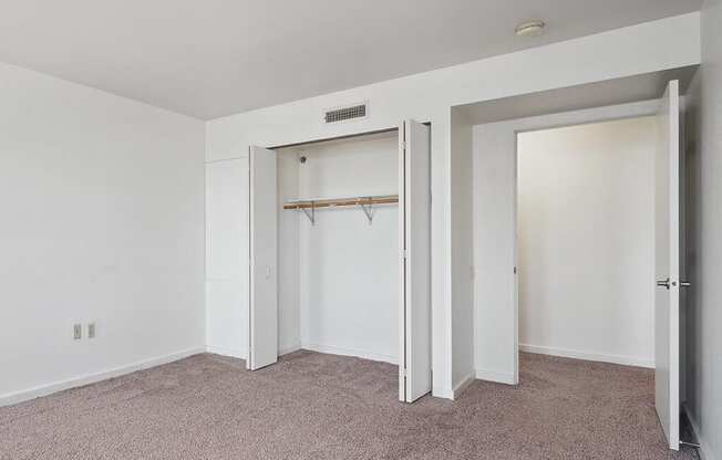 a bedroom with white walls and a closet and a carpeted floor