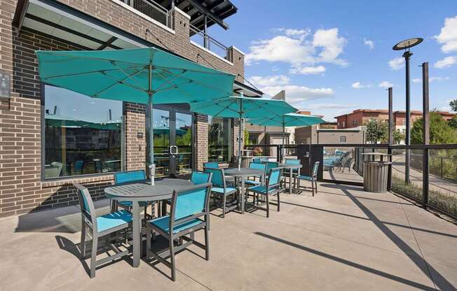 A patio with tables and chairs under a green awning.