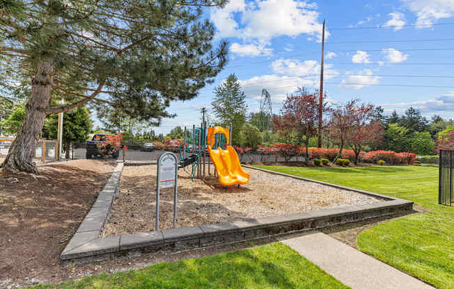 A playground with a yellow slide and a sign.
