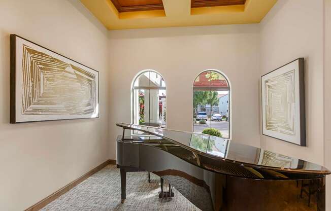 A room with a piano and two framed artworks on the wall.