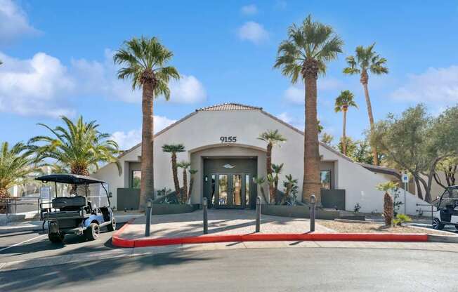 A white building with palm trees in front of it.