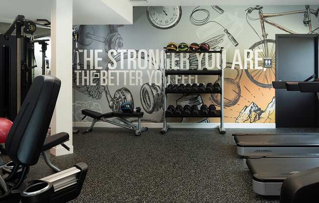 A gym room with a wall mural that says "The stronger you are, the better you feel.".