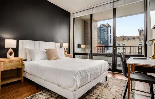 A bedroom with a large bed, a desk, and a chair.