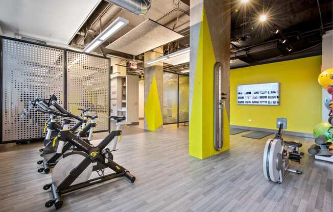 a gym with cardio equipment and weights in a building with yellow walls