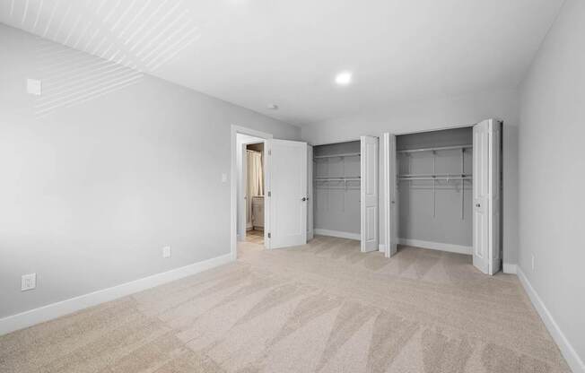 a living room with white walls and carpet and a closet with doors