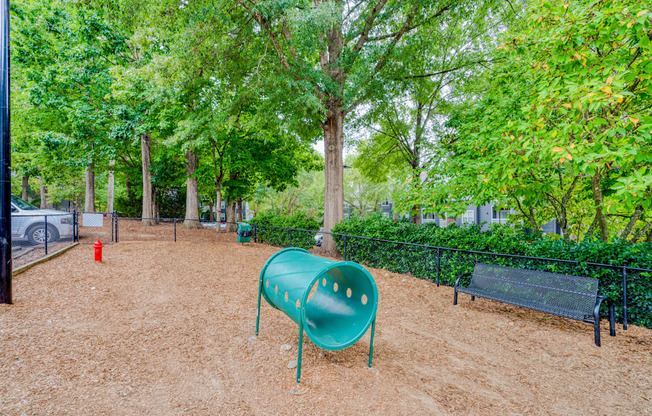 A playground with a green slide and a red fire hydrant.