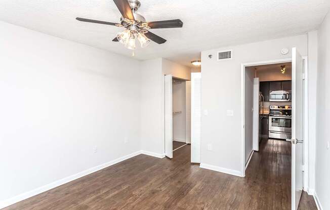 A room with a ceiling fan and wooden floors.