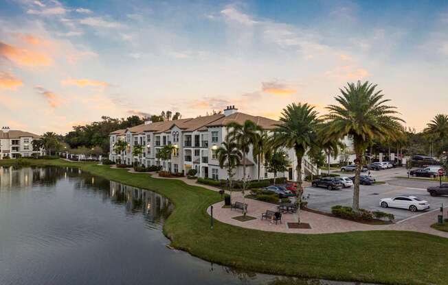 A serene lake surrounded by apartment buildings and palm trees under a clear sky.