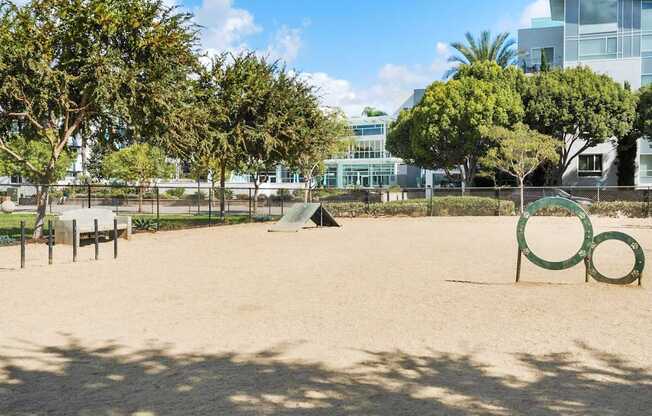 A playground with a sandy area, a slide, and a green ring.