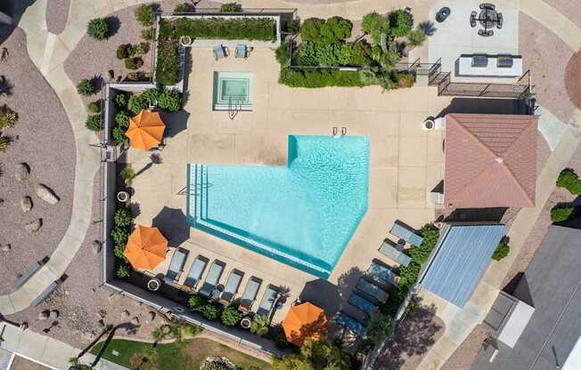 An aerial view of a pool surrounded by orange umbrellas and lounge chairs.