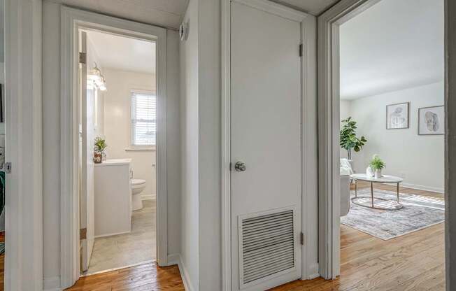 A white door is open to a room with a table and a potted plant.