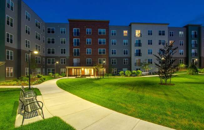 a park with a bench and an apartment building at night