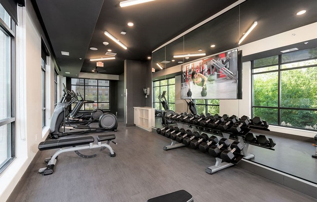 a gym with weights and a tv on the wall