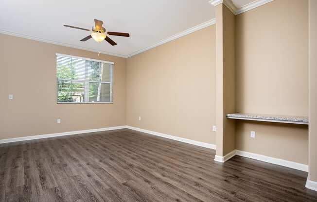 an empty bedroom with a ceiling fan and a window