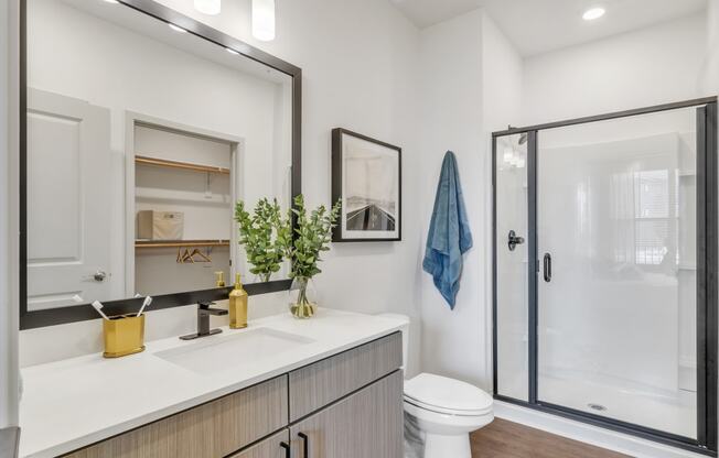 a bathroom with a shower, a sink, and a mirror at Apex apartments in Colorado Springs, CO