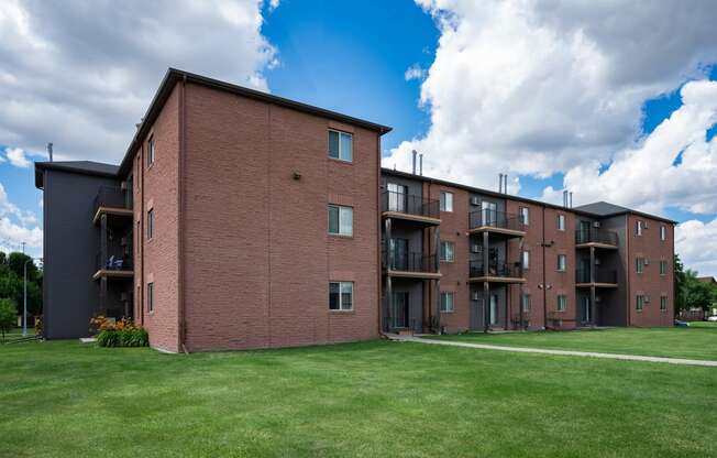 a large brick apartment building with a green lawn