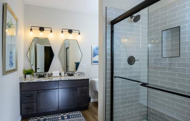 A bathroom with a black vanity and a glass shower.