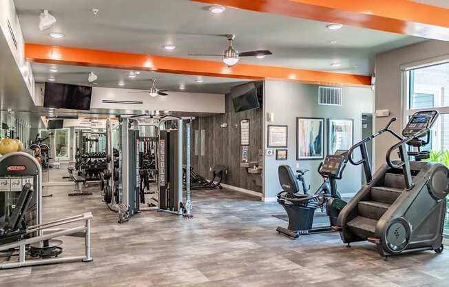 A gym with a variety of equipment including treadmills, weights, and exercise machines.
