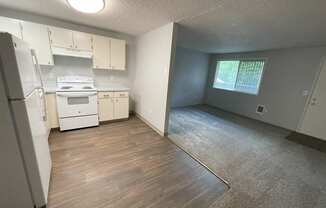 A kitchen with white appliances and wooden floors.